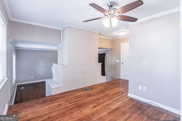 empty room with baseboards, wood finished floors, visible vents, and crown molding