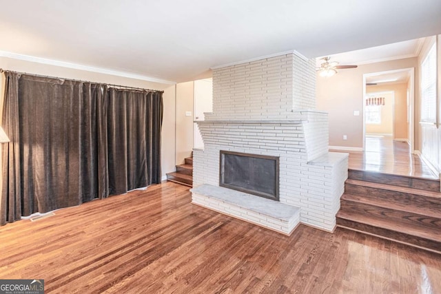 unfurnished living room with a fireplace, wood finished floors, visible vents, a ceiling fan, and ornamental molding