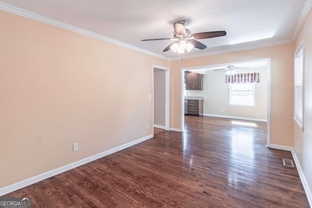 empty room with ornamental molding, dark wood-style flooring, visible vents, and baseboards