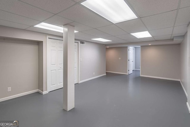 finished basement with a paneled ceiling, baseboards, and visible vents