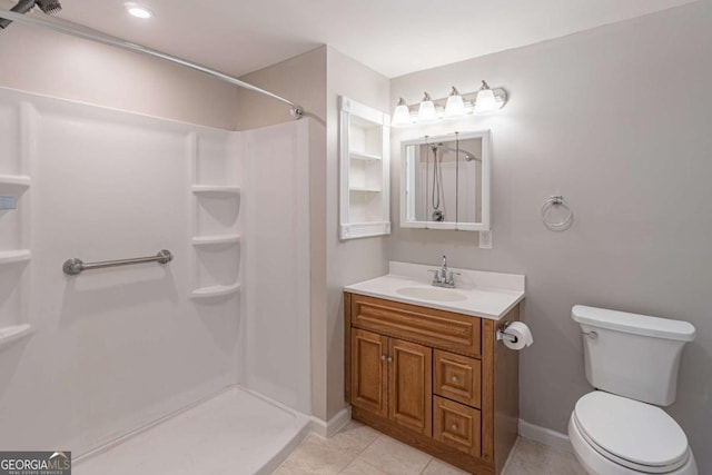 bathroom featuring toilet, a shower stall, vanity, tile patterned flooring, and baseboards