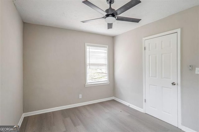 empty room featuring ceiling fan, baseboards, and wood finished floors