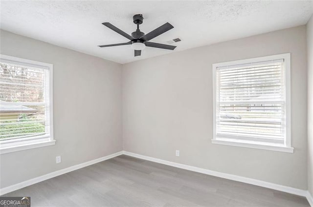 empty room featuring visible vents, ceiling fan, a textured ceiling, wood finished floors, and baseboards