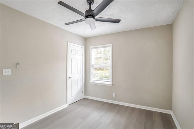 spare room featuring a textured ceiling, ceiling fan, wood finished floors, and baseboards