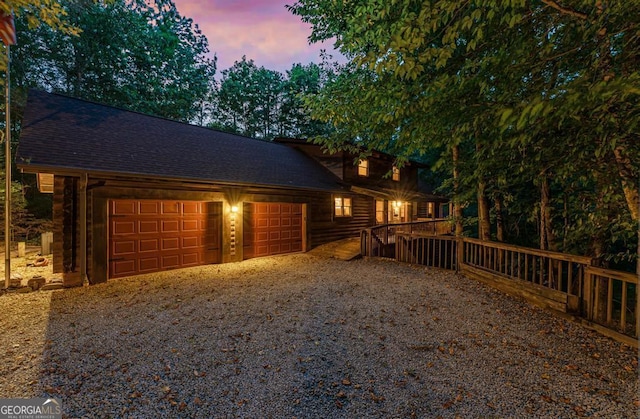 exterior space with a garage, a shingled roof, and gravel driveway