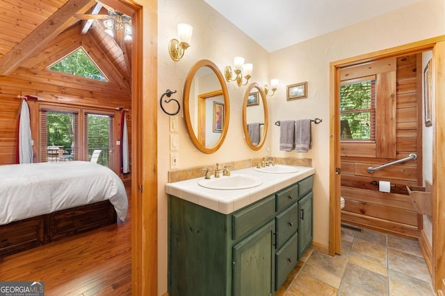 bathroom featuring vaulted ceiling with beams, a healthy amount of sunlight, and a sink