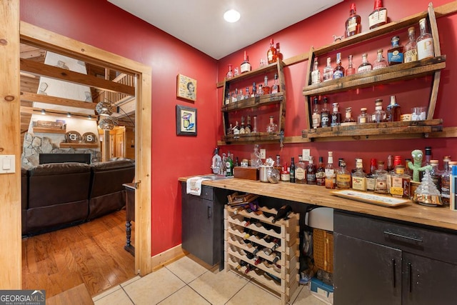 bar with a bar, baseboards, a sink, and light tile patterned flooring