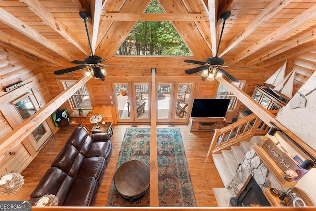 unfurnished living room with wooden ceiling, beamed ceiling, wooden walls, and stairs