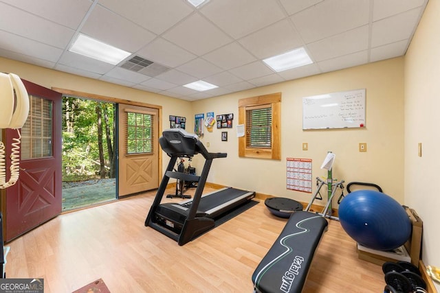 workout area featuring baseboards, visible vents, a drop ceiling, and wood finished floors