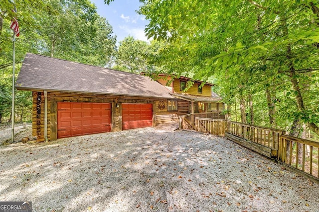 view of front of house featuring driveway, a garage, log siding, and roof with shingles