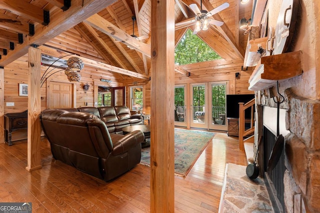 living area with a ceiling fan, beam ceiling, wooden ceiling, and wooden walls