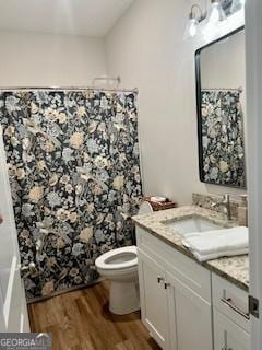 bathroom featuring vanity, curtained shower, wood finished floors, and toilet