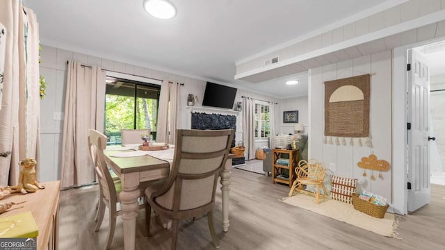 dining space with crown molding, visible vents, a fireplace, and wood finished floors