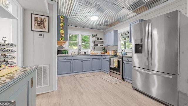 kitchen featuring open shelves, visible vents, light wood-style flooring, appliances with stainless steel finishes, and a sink