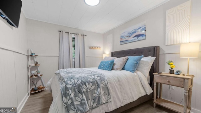 bedroom with wood finished floors and wainscoting