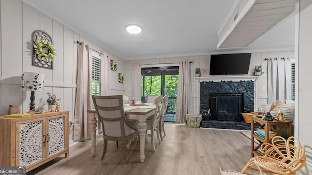 dining space with light wood-style flooring, a premium fireplace, and crown molding