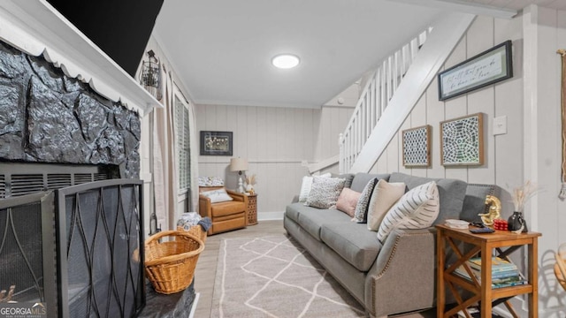 living room featuring a fireplace with raised hearth, wood finished floors, and stairs