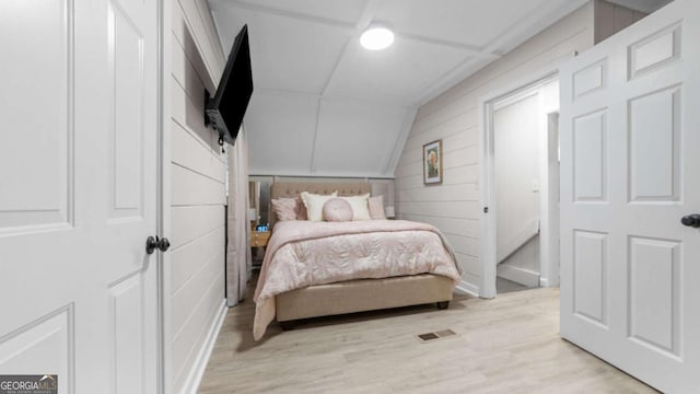 bedroom with lofted ceiling, visible vents, and light wood-style floors