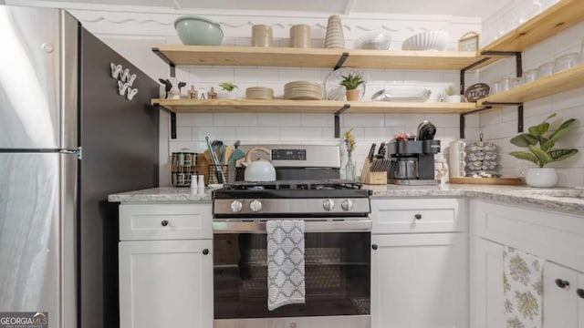 kitchen with open shelves, tasteful backsplash, appliances with stainless steel finishes, white cabinets, and light stone countertops