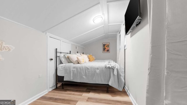 bedroom with vaulted ceiling, baseboards, and wood finished floors