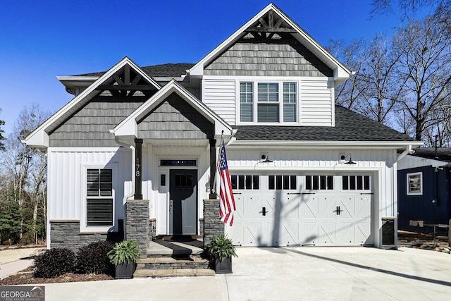 view of front of house with concrete driveway, stone siding, roof with shingles, an attached garage, and board and batten siding