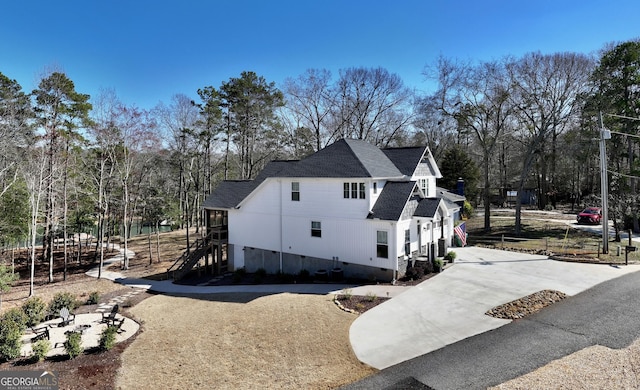 view of home's exterior with concrete driveway, crawl space, and roof with shingles