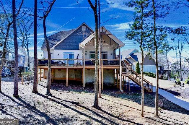 back of property with a shingled roof, stairway, and a wooden deck