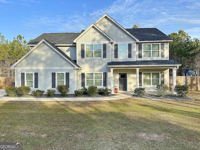 view of front of property with a shingled roof, fence, board and batten siding, and a front yard