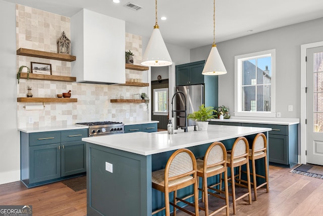 kitchen with open shelves, visible vents, appliances with stainless steel finishes, and a kitchen island with sink