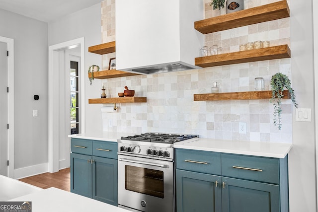 kitchen with open shelves, blue cabinetry, custom exhaust hood, and stainless steel stove