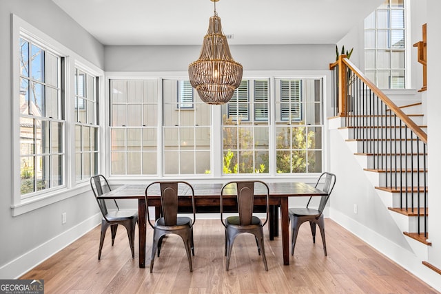 dining space featuring a notable chandelier, stairs, baseboards, and wood finished floors