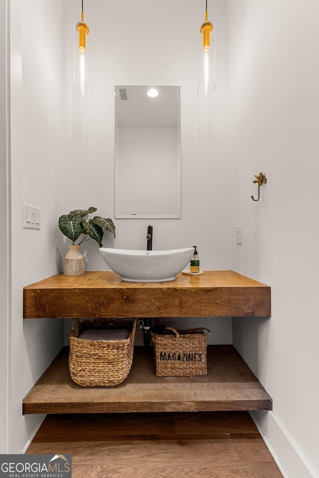 bathroom with a sink, visible vents, baseboards, and wood finished floors