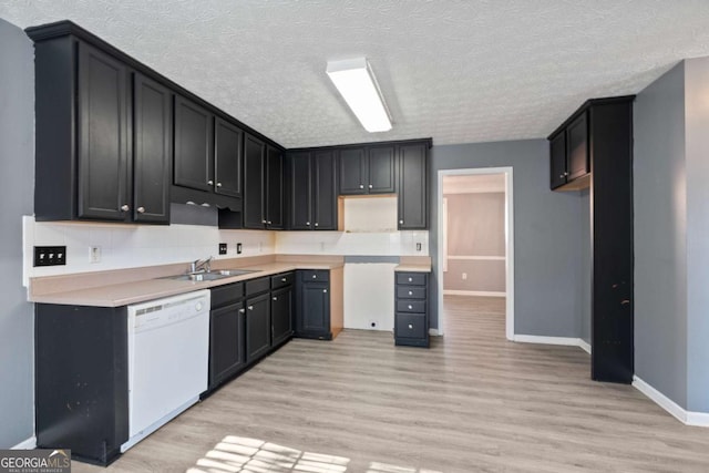 kitchen with dishwasher, light wood finished floors, a sink, and a textured ceiling