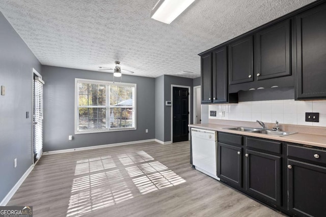 kitchen featuring light wood finished floors, baseboards, decorative backsplash, white dishwasher, and a sink