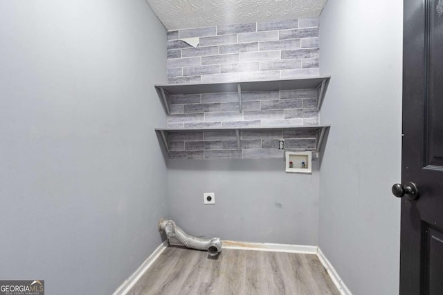 clothes washing area featuring laundry area, baseboards, wood finished floors, hookup for an electric dryer, and washer hookup