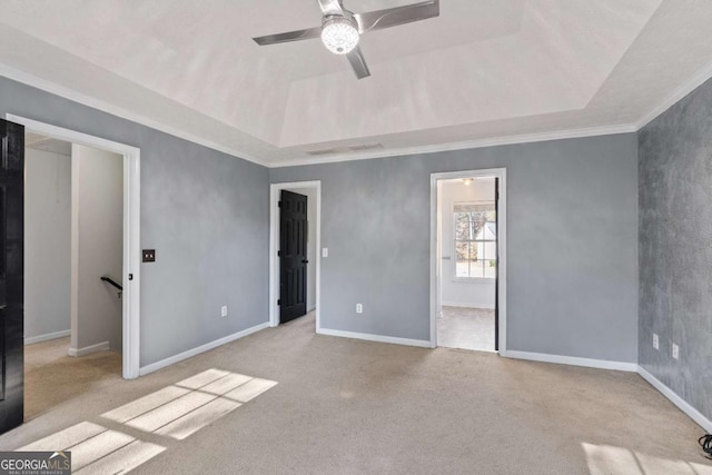 unfurnished bedroom featuring carpet floors, a tray ceiling, ornamental molding, ceiling fan, and baseboards