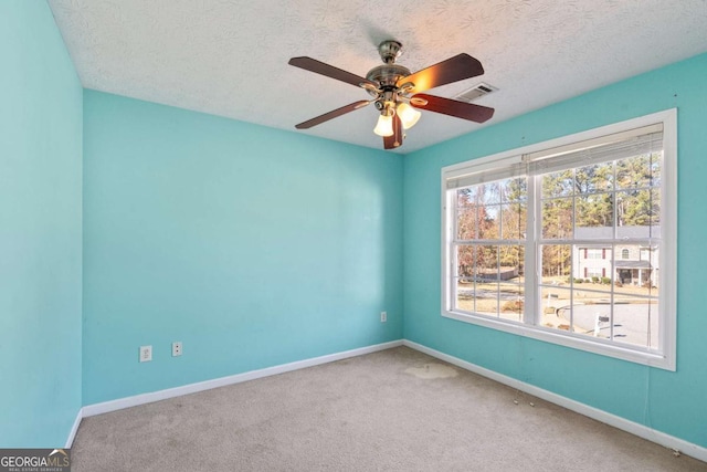 carpeted spare room with a textured ceiling, ceiling fan, visible vents, and baseboards