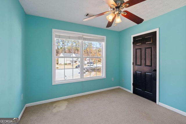 empty room featuring a ceiling fan, carpet, visible vents, and baseboards