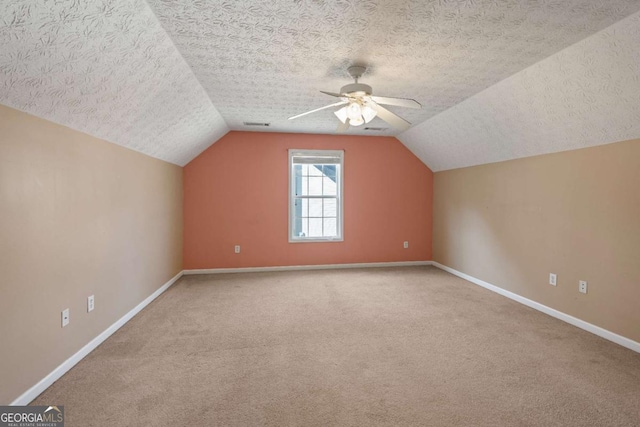 bonus room featuring lofted ceiling, carpet flooring, a textured ceiling, and baseboards