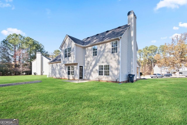 back of property with a patio area, a yard, and a chimney