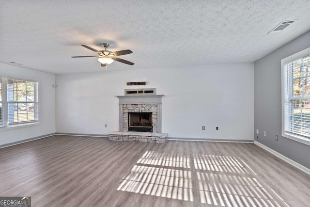 unfurnished living room featuring visible vents, a fireplace, baseboards, and wood finished floors