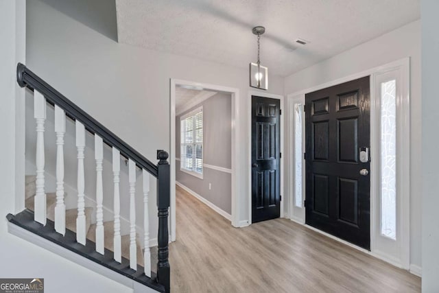 entrance foyer featuring light wood finished floors, stairs, and baseboards