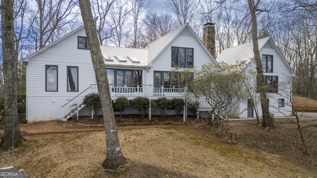 view of front of property with metal roof, stairway, and a chimney