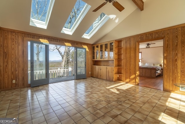 unfurnished living room featuring beamed ceiling, tile patterned floors, a ceiling fan, and wooden walls