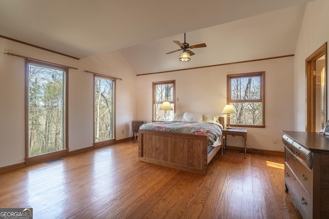 bedroom with lofted ceiling, visible vents, baseboards, and wood finished floors