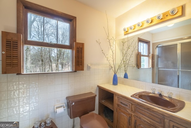 full bath featuring toilet, a wainscoted wall, vanity, tile walls, and a shower stall