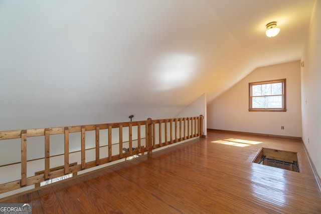 additional living space with vaulted ceiling, baseboards, and wood finished floors