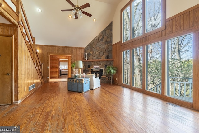 unfurnished living room with wood walls, wood finished floors, and visible vents