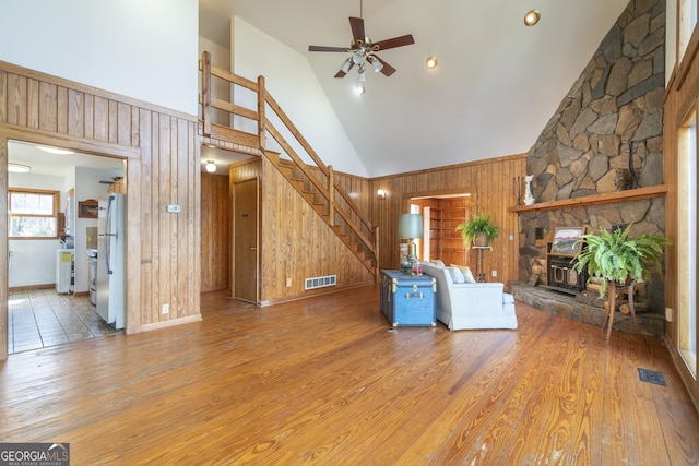 unfurnished living room featuring visible vents, wood walls, stairway, and wood finished floors