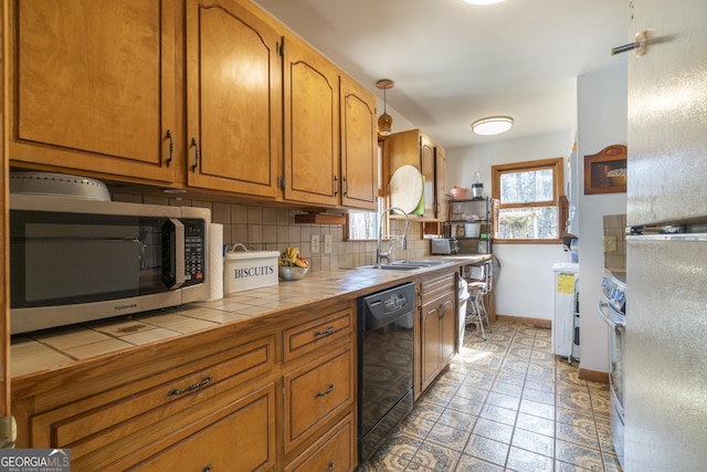 kitchen with tile countertops, a sink, black dishwasher, tasteful backsplash, and stainless steel microwave